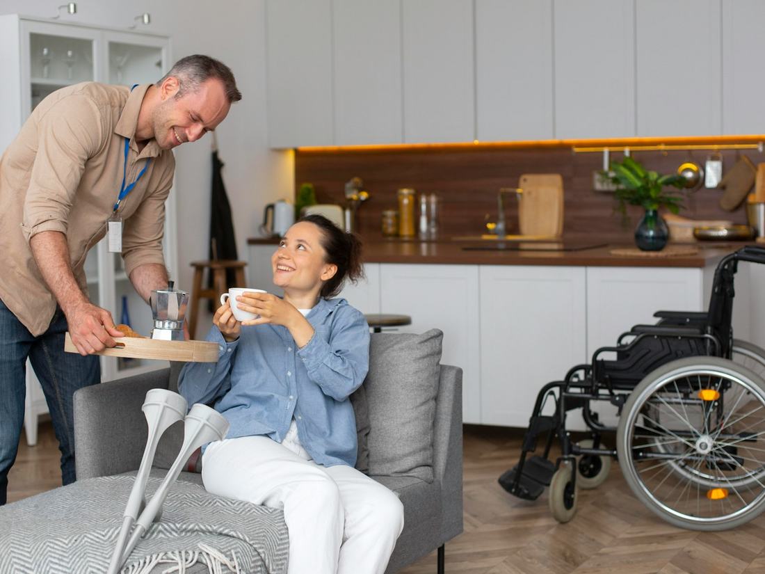 A man in a wheelchair and a companion talking at home