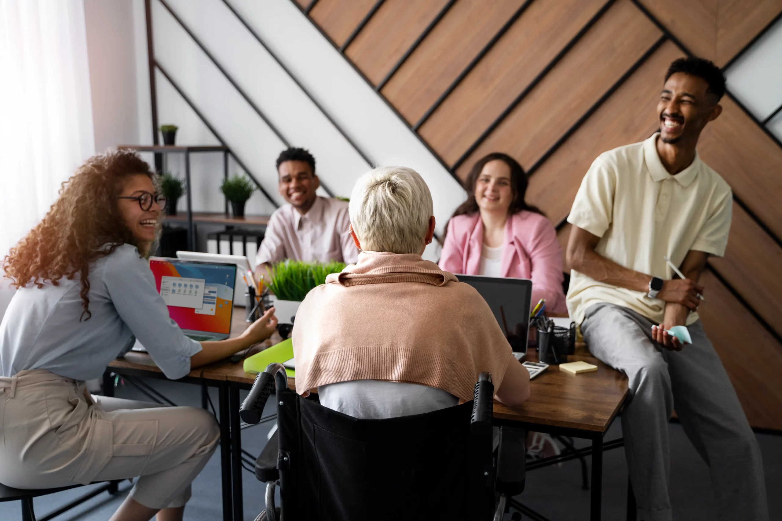 Several individuals gathered at a table, focused on their laptops, engaged in a productive discussion.
